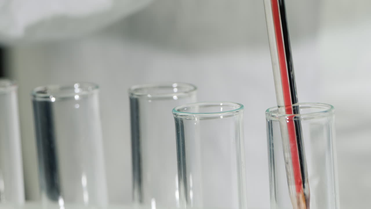 기술자가 테스트 튜브 1에 피를 떨어뜨립니다.