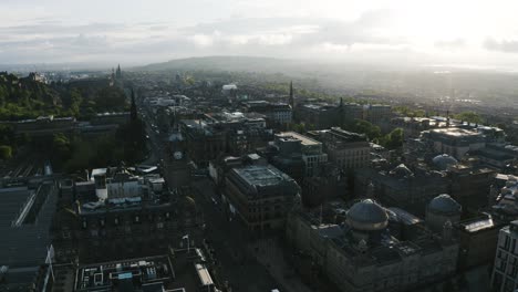 drone shot of downtown edinburgh, scotland near sunset with a clock tower overlooking the neighborhood