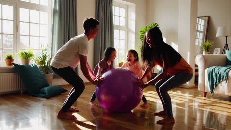 a family playing with a large exercise ball in their living room