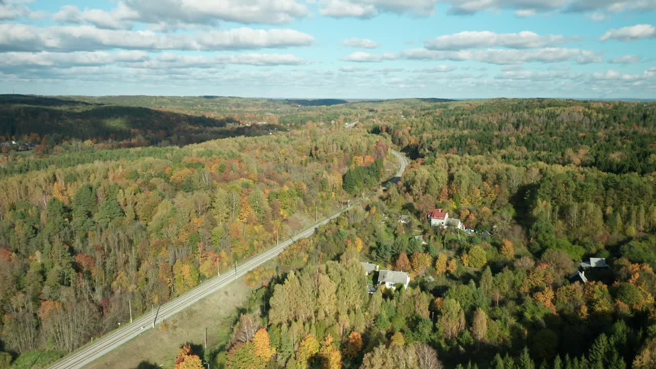 AERIAL: beautiful fall color trees from above drone shot, red yellow orange green, forest video flying over autumn near rail road