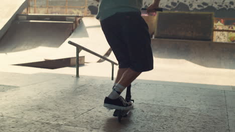 Young-scooter-rider-performing-tricks-at-skate-park.-Active-leisure-outdoors.