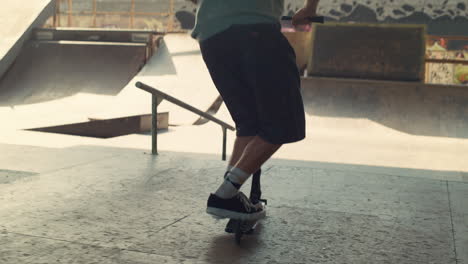 young scooter rider performing tricks at skate park. active leisure outdoors.