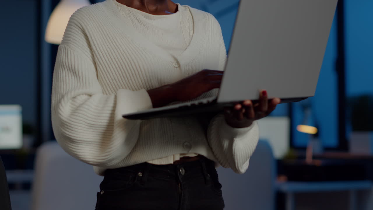 Manager africano stanco che guarda in camera sospirando, con il laptop in mano mentre digita