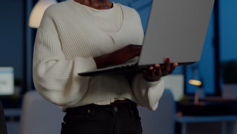 un gerente africano cansado mirando a la cámara suspirando sosteniendo una computadora portátil escribiendo en ella