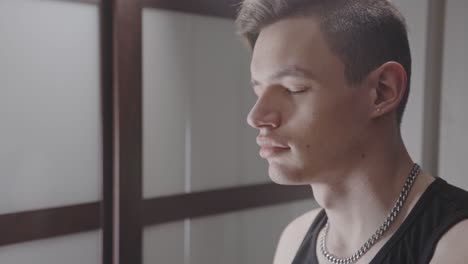 side view of young man meditating with closed eyes in his room