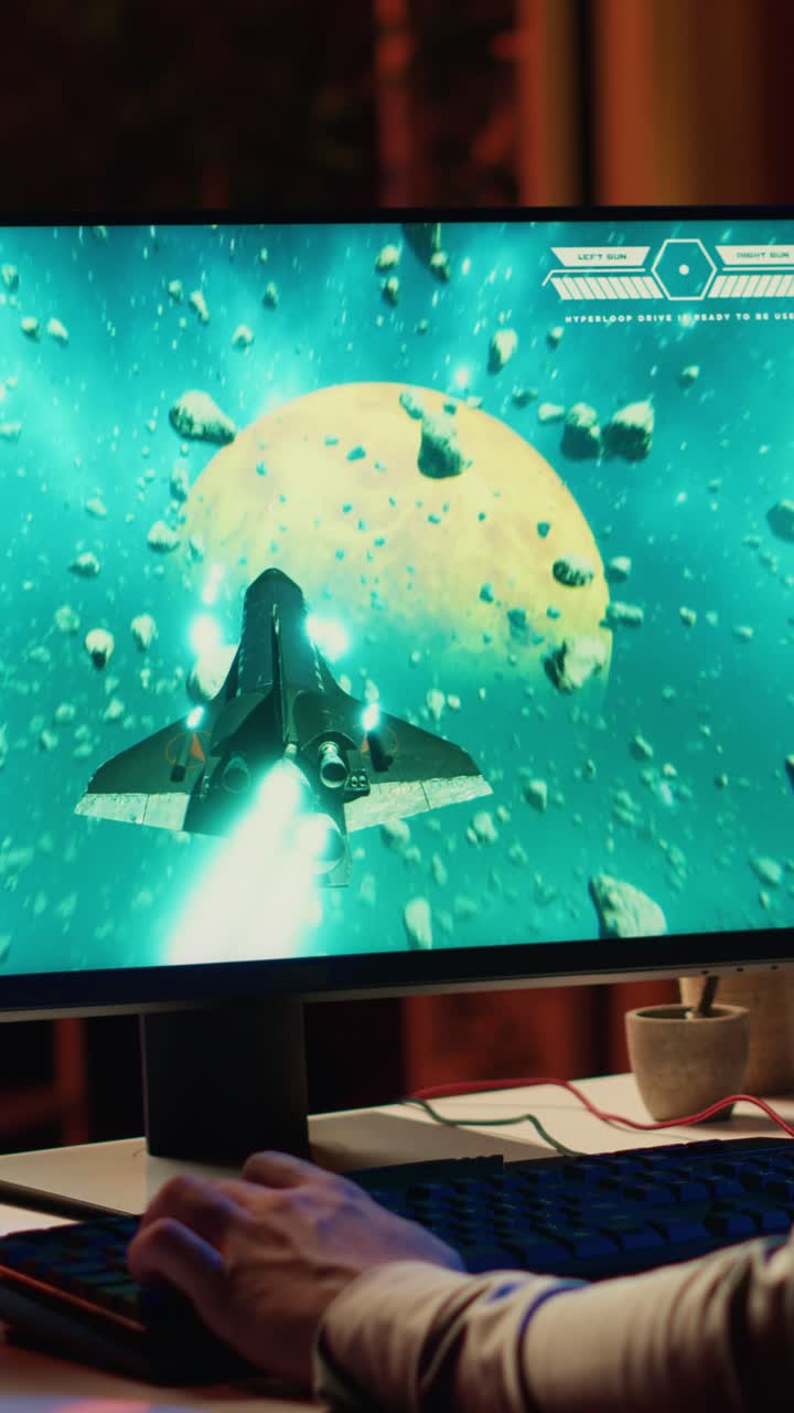 Video verticale. Un uomo usa una tastiera da gaming per pilotare un’astronave in un videogioco di fantascienza, primo piano sullo schermo del computer
