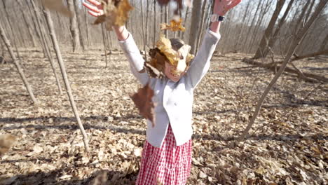 happy little girl throwing a pile of leaves into the air, slow motion