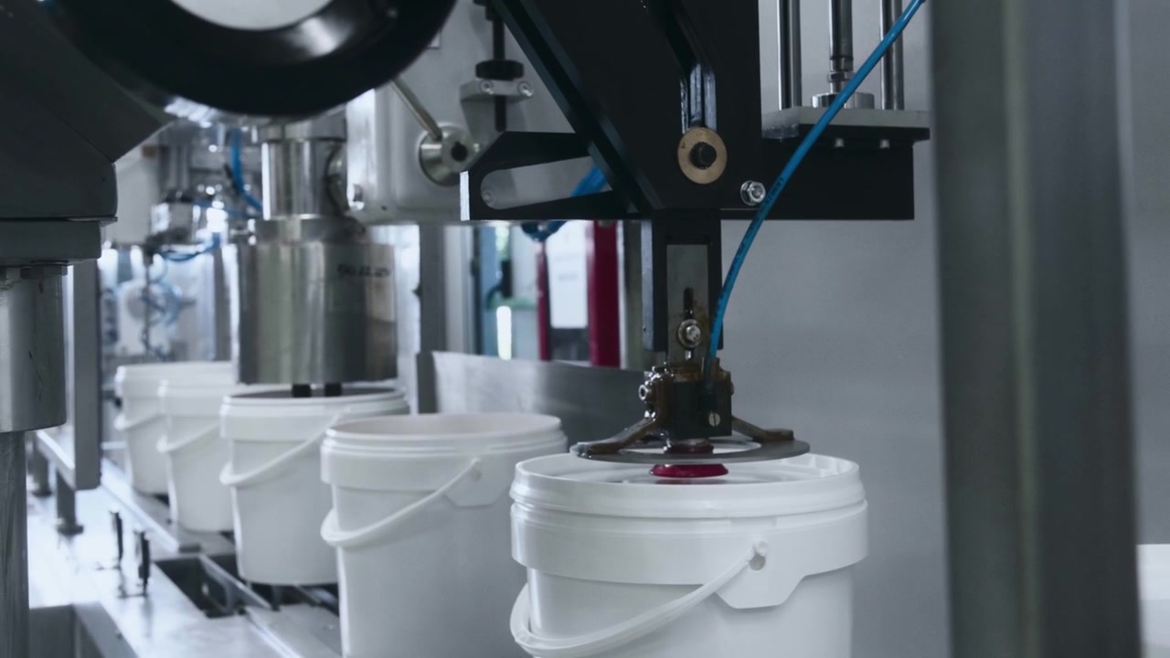 White plastic containers traveling through an industrial conveyor system inside a modern manufacturing facility, showcasing automated packaging and factory workflow efficiency