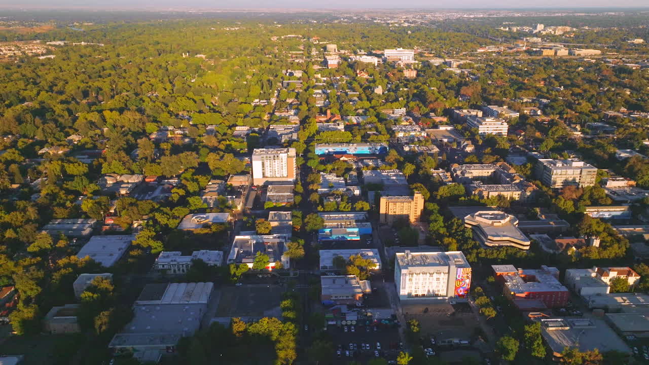 Vast urban panorama with lots of greenery on sunny daytime. Dense architecture of the city from aerial perspective.