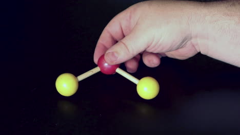 ball and stick model of water being moved around on a black lab bench