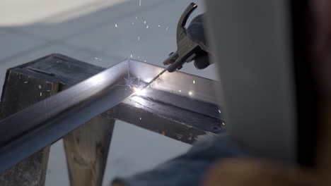 welding metal frame while sparks are shooting away close up in slow motion
