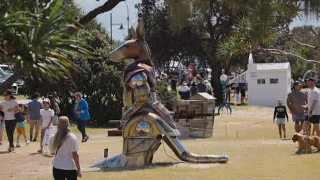 personas interactuando con la escultura de canguro en la playa