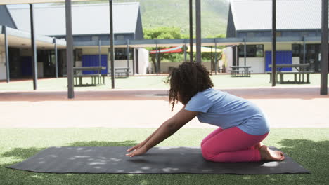 chica biracial practicando yoga en la escuela