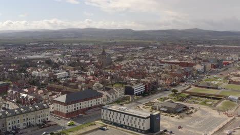 An-aerial-view-of-Rhyl-promenade-and-seafront-on-a-cloudy-day,-flying-away-from-the-town-centre-over-the-promenade,-North-Wales,-UK