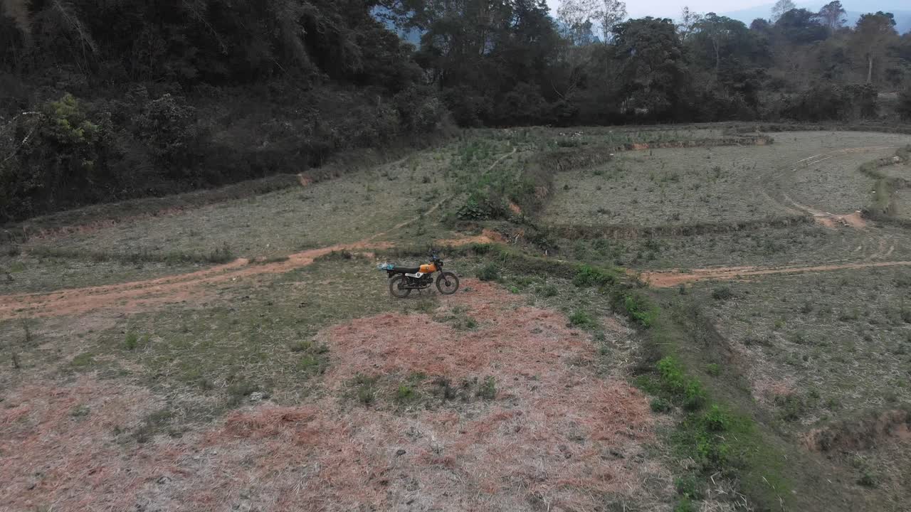 la motocicleta está estacionada en medio de un prado en el campo de laos, aérea