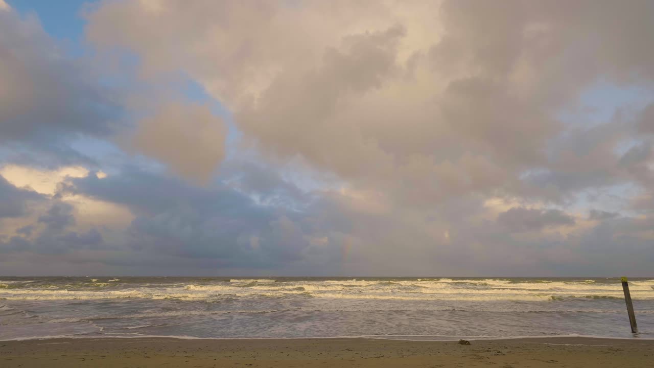arco iris en la playa frente a la costa de los países bajos