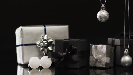 video of silver baubles christmas decorations and gifts with copy space on black background