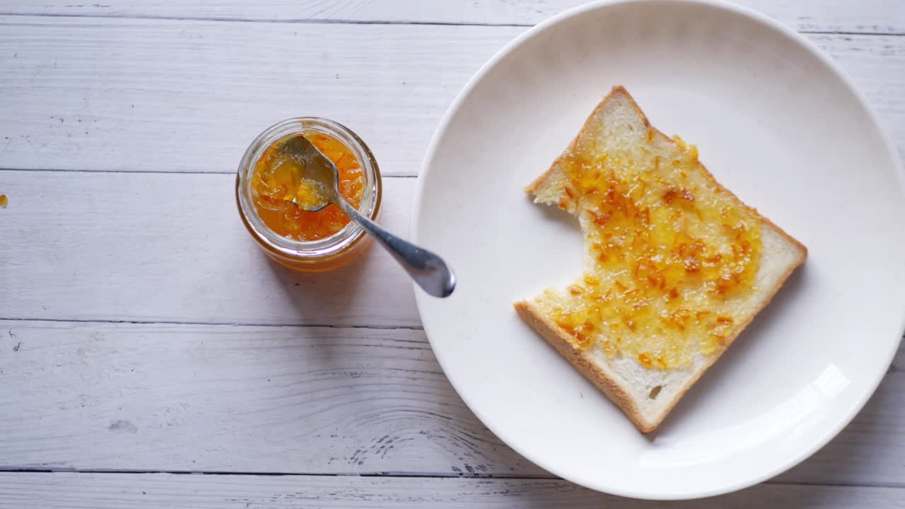 Orange fruit spread on a bread on table ,