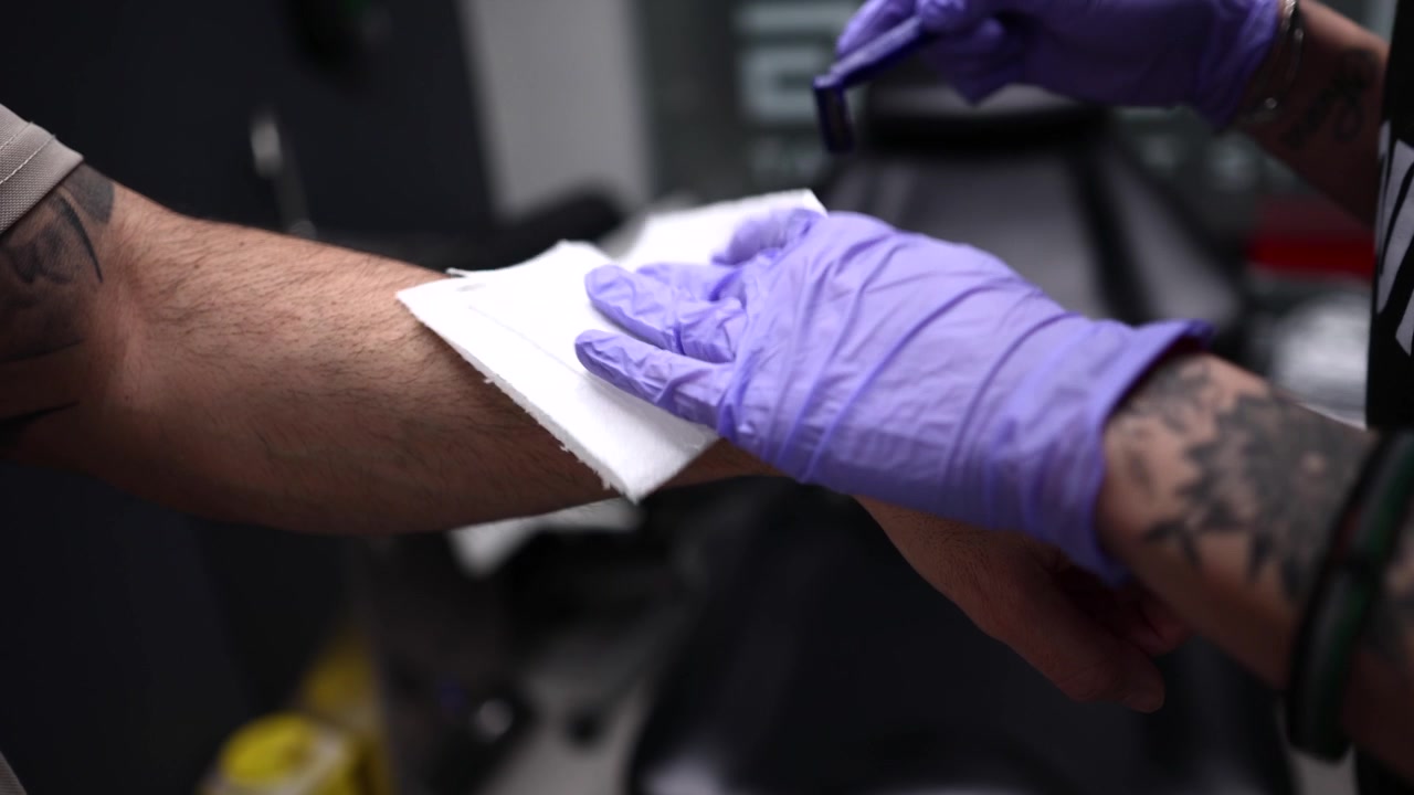 Tatuatore che rade il braccio del cliente prima di tatuare