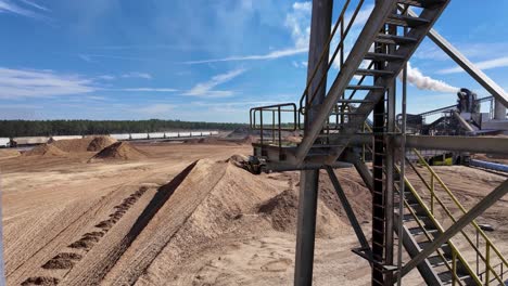 panning shot revealing industrial equipment and mounds of wood chips