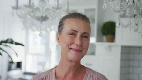 Portrait-of-smiling-senior-caucasian-woman-looking-at-camera-in-kitchen