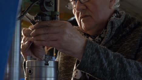 Senior-caucasian-worker-putting-drill-bit-in-a-drilling-machine-in-a-workshop