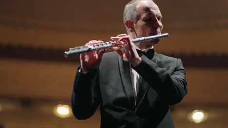 talented flutist is playing neoclassic music by flute portrait of musician in philharmonic hall