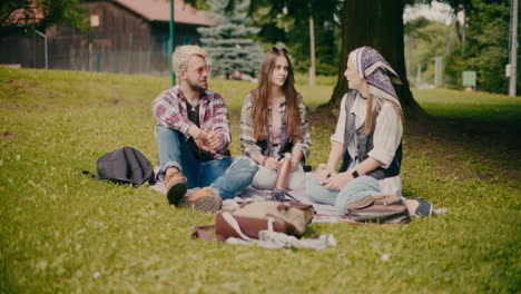 Friends-Sitting-And-Talking-On-Grass-At-Park