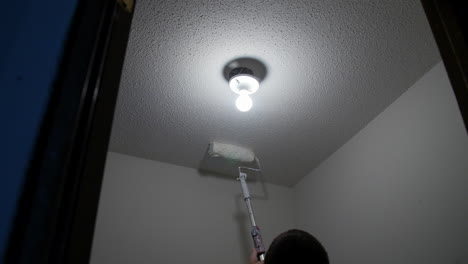 Man-Paints-Ceiling-With-White-Paint-Using-A-Roller