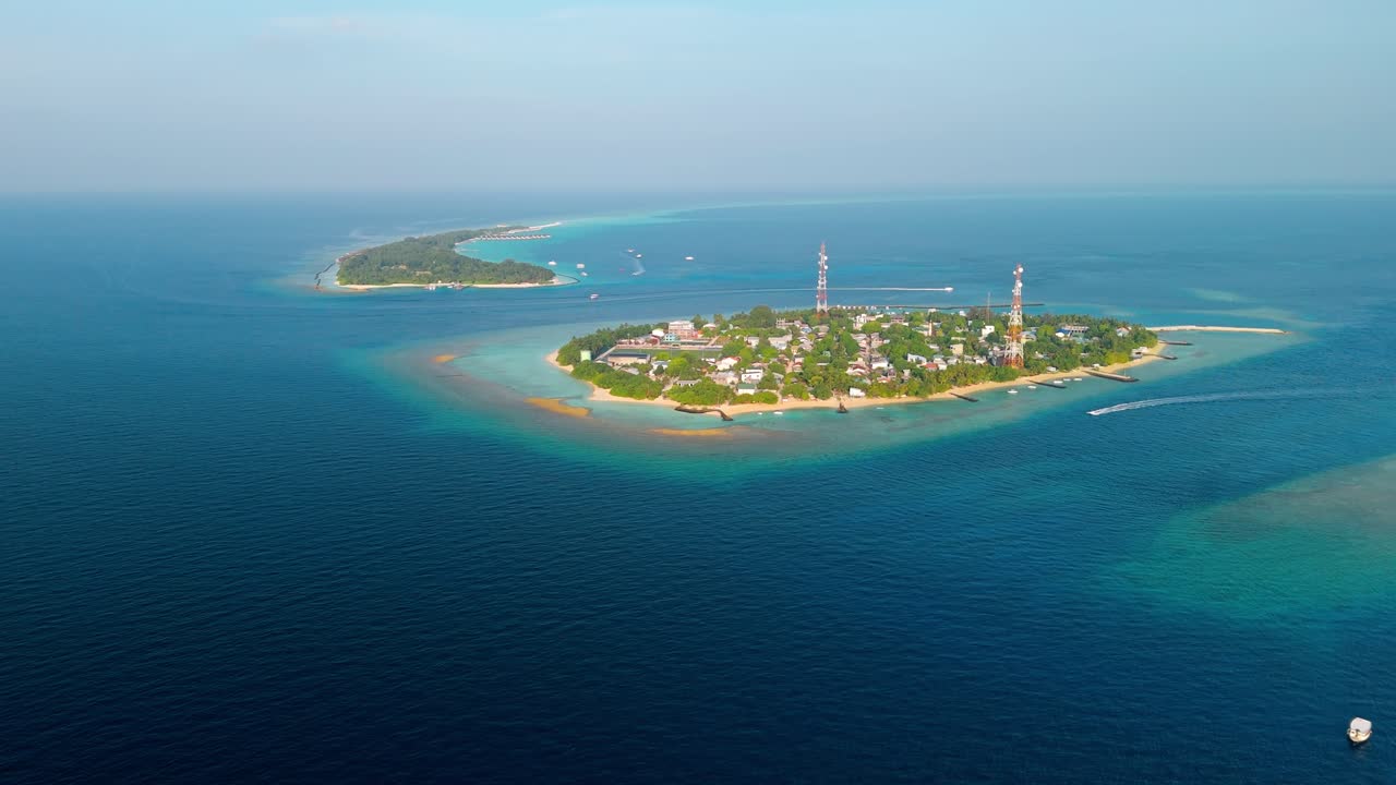 A stunning aerial drone view showcasing Rasdhoo Island surrounded by crystal-clear turquoise waters and vibrant coral reefs in the Maldives.