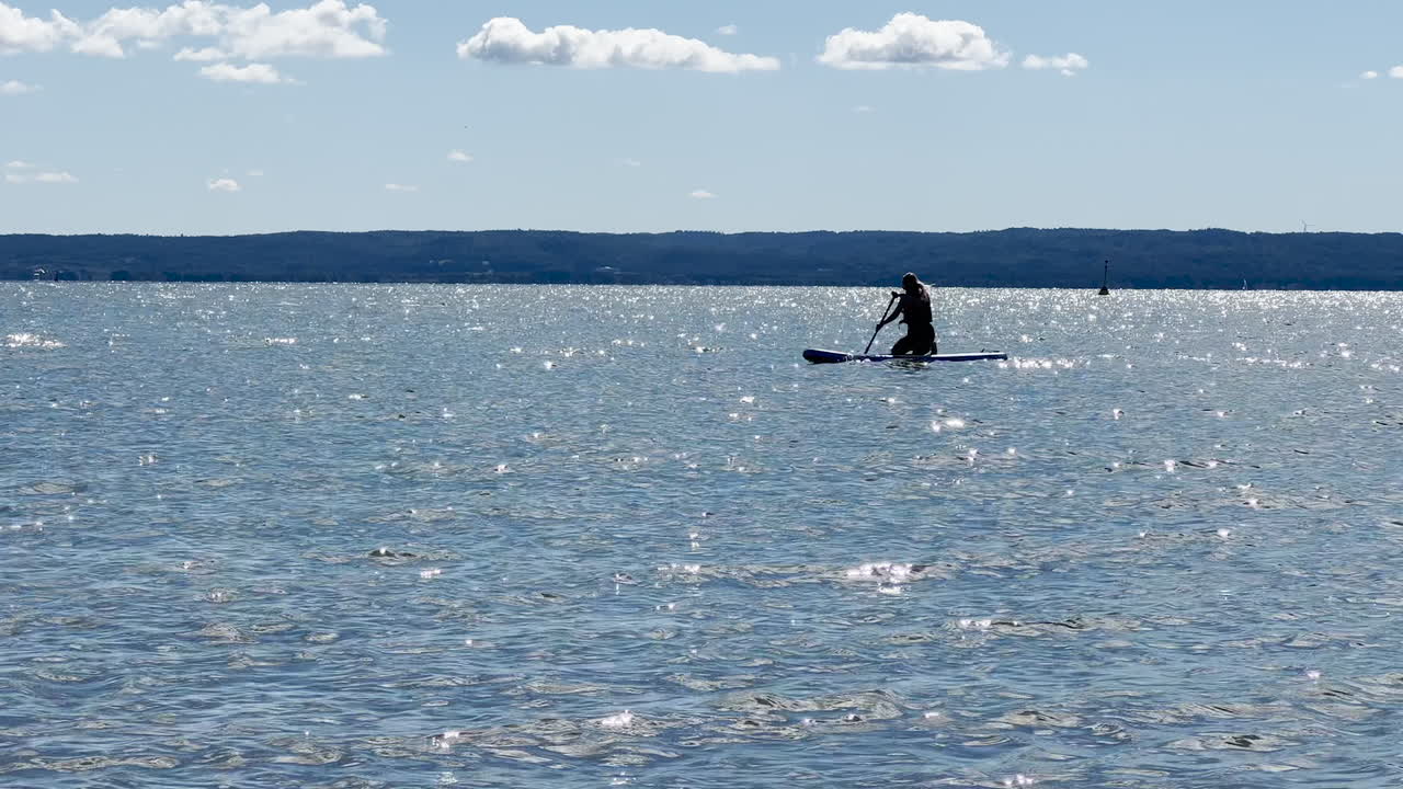 silueta de persona en tabla de surf remando en el mar en verano