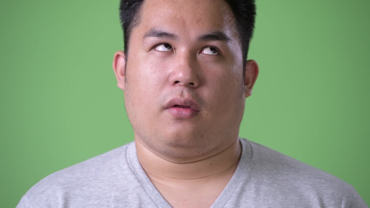 초록색 배경에 젊은 잘생긴 과체중 아시아인