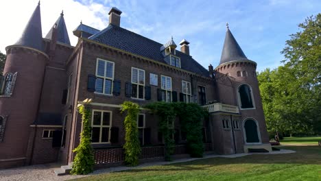 a smooth daytime camera pan reveals a brick castle with turrets and lush botanical gardens under clear blue skies in lisse, netherlands