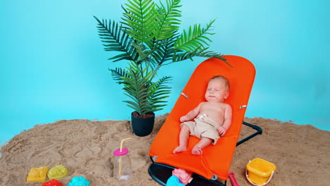 cute caucasian infant wearing beige shorts only lies in a baby chair. little kid starts to cry. improvised beach vacation concept.
