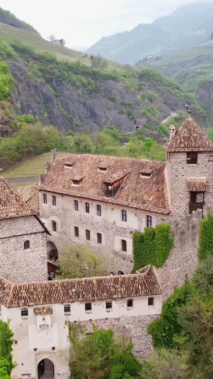 Filmato aereo verticale del Castello di Roncolo circondato da verde e colline.