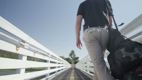 Ein-Golfspieler-Geht-Einen-Gehweg-Von-Der-Kamera-Weg,-Während-Die-Kamera-Zurückfährt