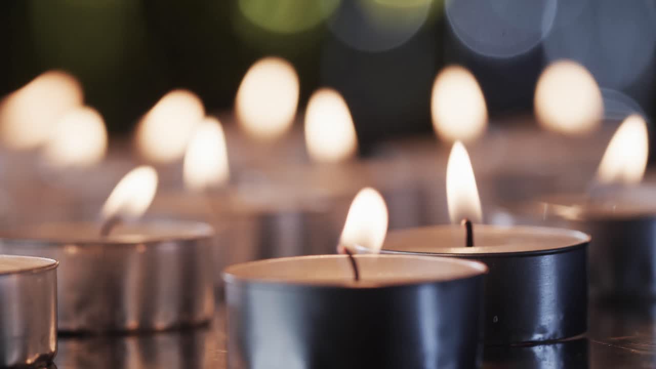 Video di lumini a candela con fiamme bianche e spazio per il testo con effetto bokeh su sfondo nero