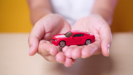mano de mujer con concepto de coche rojo para seguros, compra, alquiler, combustible o servicio y costos de reparación