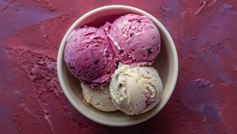 a bowl of ice cream with vanilla and berry scoops