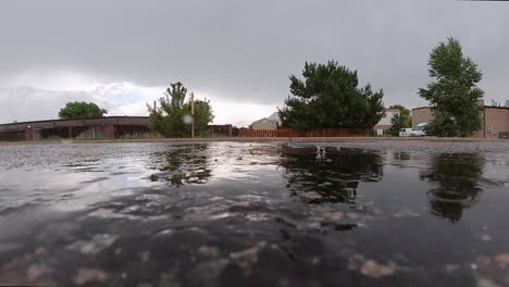 Gotas-De-Lluvia-Golpeando-Un-Charco-En-Un-Camino-De-Asfalto