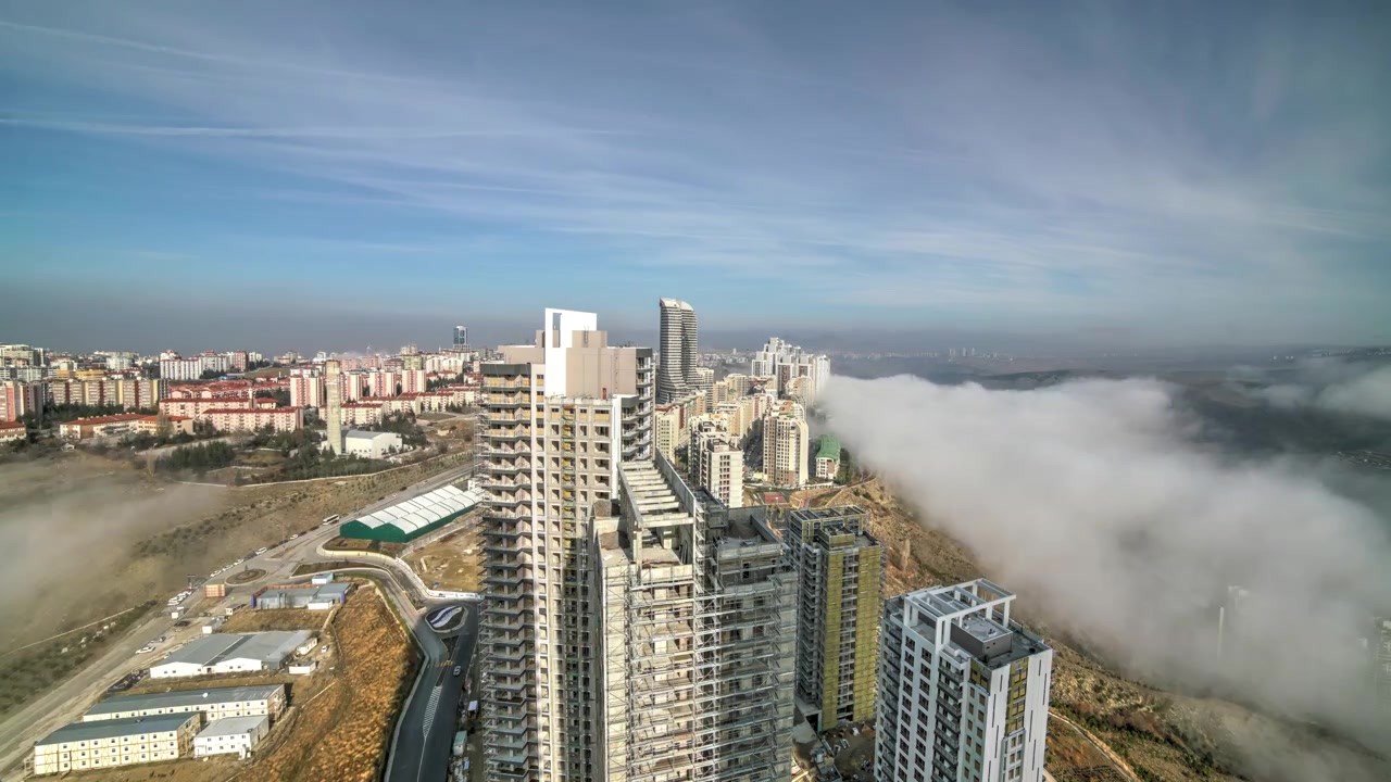 Time-lapse aereo della nebbia mattutina che si dirada sopra lo skyline di una città moderna