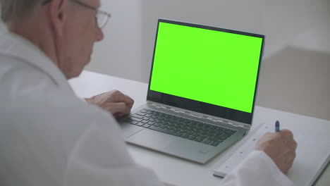 cuaderno con pantalla verde en la mesa del terapeuta que trabaja en la clínica concepto de cita con el médico en línea