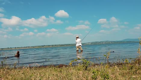 girl bass fishing while standing in a beautiful lake on a sunny day