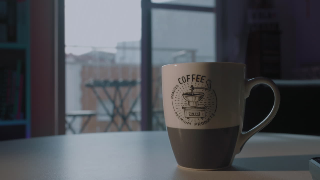 Tazza da caffè con design del logo su tavolo vicino a finestra