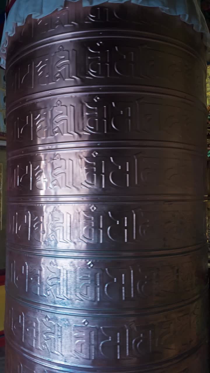 Traditional big, continuously spinning prayer wheel with sacred mantras in a Buddhist stupa.