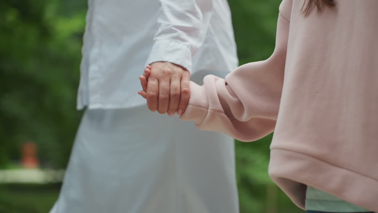 가족이 행복하게 산책합니다. 엄마와 딸이 야외에서 유대감을 나눕니다. 엄마와 아이가 평화로운 공원 산책 중 손을 잡고 걷습니다. 자연 속에서 엄마와 딸이 가족애를 나누며 다정하게 산책하는 모습.