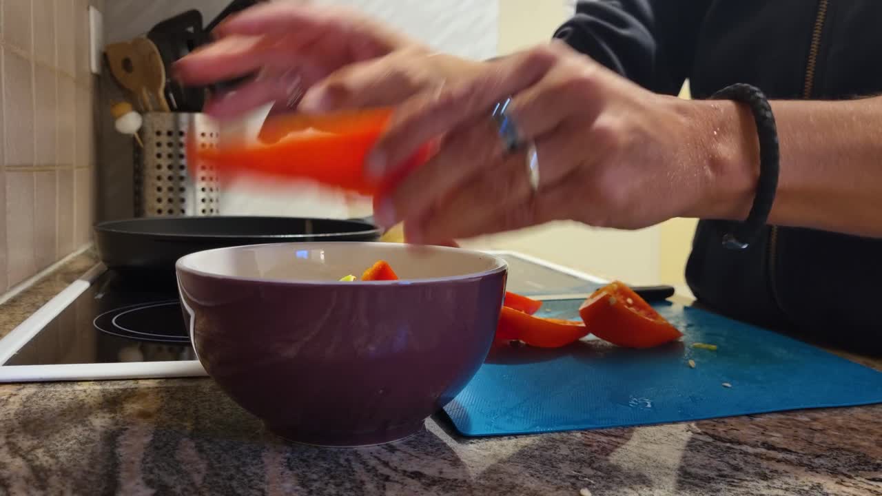 Close-up of a woman’s hands removing seeds from fresh red bell peppers in her home kitchen, preparing a nutritious vegetarian dish for her family, reflecting Swiss lifestyle
