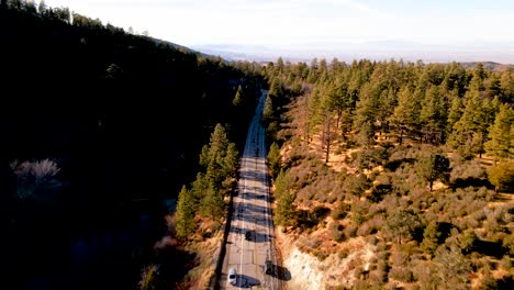 cars driving on mountain road next to lake