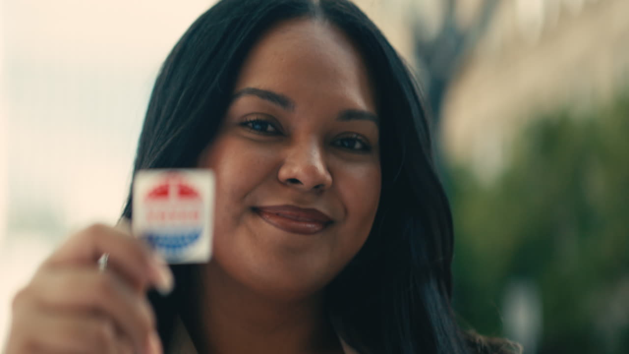 Donna che tiene in mano un adesivo con la scritta “Ho votato”