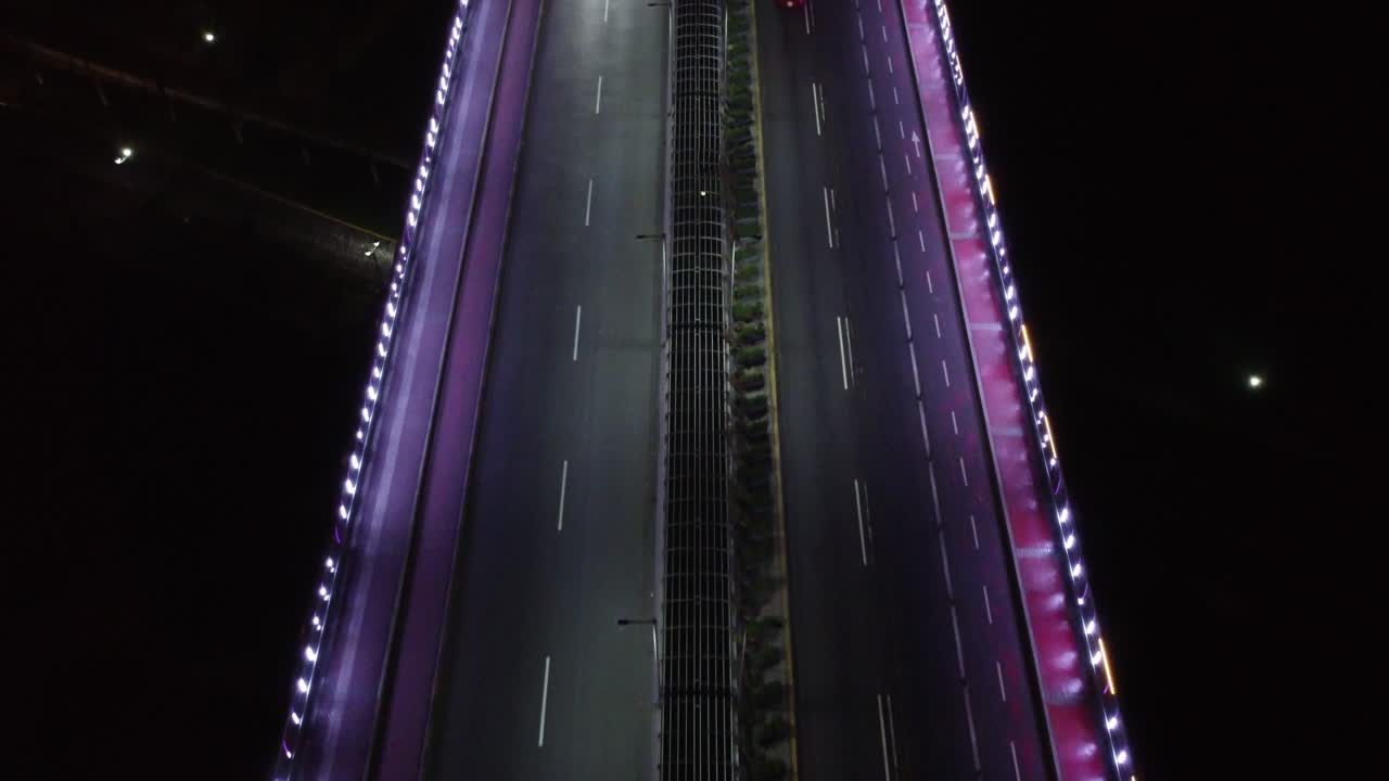 Video aereo di un ponte di notte illuminato da luci LED viola